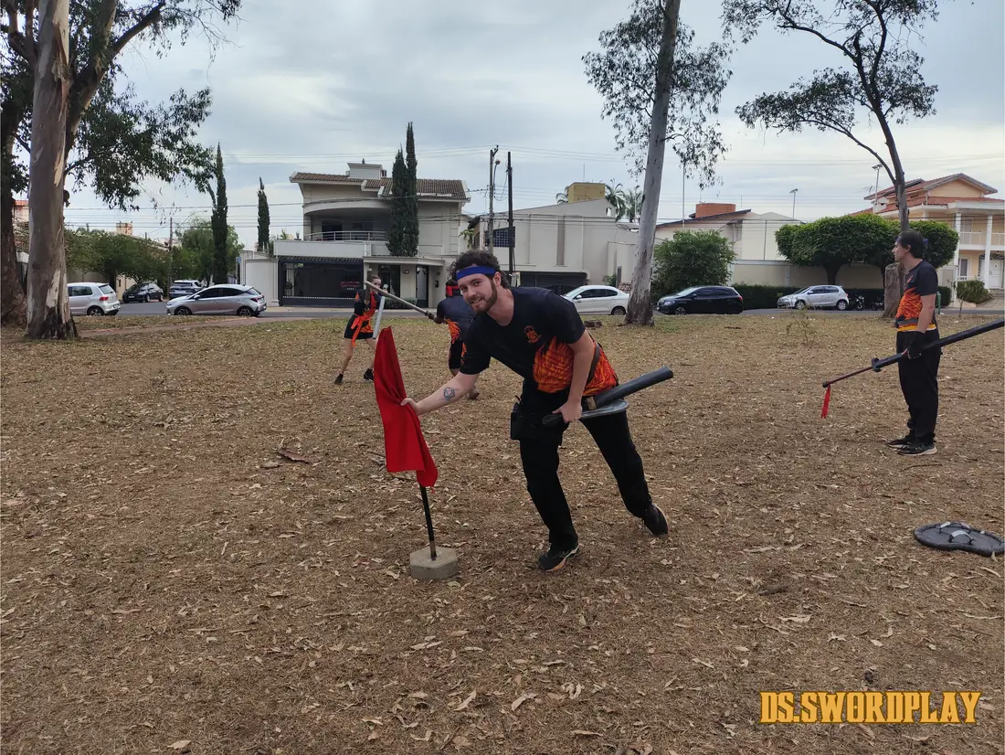 Grupo treinando com bandeiras e armas acolchoadas no parque